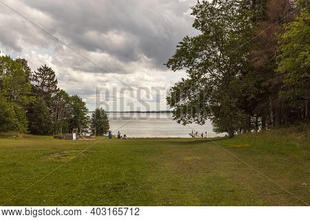 Beautiful Summer Nature Landscape View. Greengrass Field On Front And Baltic Sea On Cloudy Sky Backg