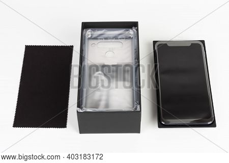 Unboxing Of Touchscreen Smartphone, Paper Box And Clean Cloth. Studio Shoot On White Background.