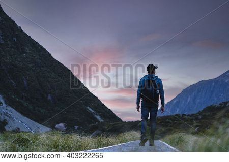 Man Walking Among The Mountains In A National Park During Sunset. Hooker Valley Track, New Zealand.