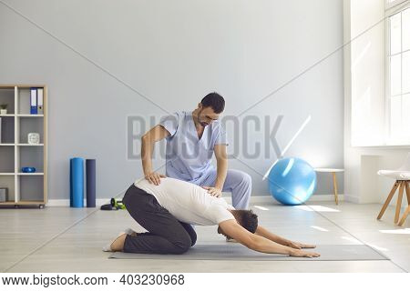 Man Doctor Osteopath Fixing Mans Back With Hands During Exersicing On Fitness Mat