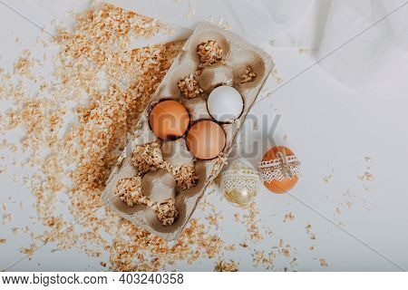 Easter Eggs In Carton Box On White Background With Sawdust Around. Easter Eggs With Lace Border Arou