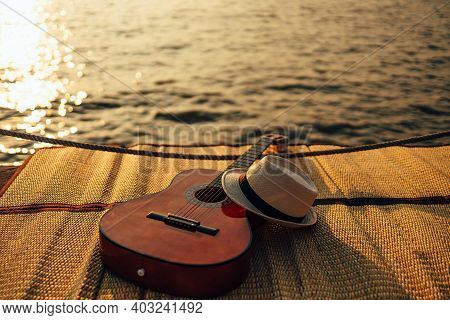Guitar And Hat On Reed Mat Near The Sea At Sunset. Travel, Vocation, Holiday, Summer Concept.