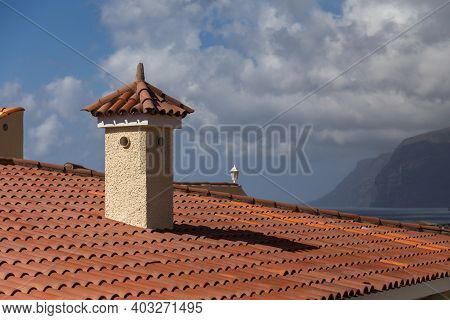 Orange Shingle Roof With Chimney. Cloudy Sky And Mountains At The Background. Los Gigantes, Tenerife