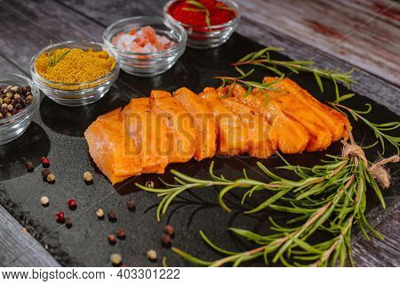 Raw Meat.chicken Fillet Thinly Sliced On A Black Ceramic Plate With Cooking Spices, Chili And Rosema