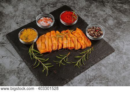 Chicken Fillet Thinly Sliced On A Black Ceramic Plate With Cooking Spices, Chili And Rosemary. Top V