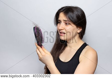 The Girl Holds A Comb For Hair With Fallen Hair. Hair Loss, Hair Care.