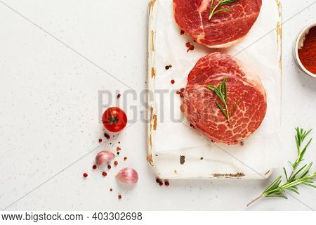 Two Fresh Parisienne Raw Steak On White Parchment Paper With Salt, Pepper And Rosmary In A Rustic St