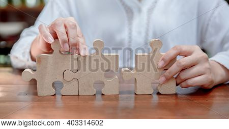 Businesswoman With Wooden Puzzle And Jigsaw For Business Succcess Concept. Teamwork And Achievement 