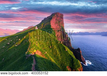 Kallur lighthouse on green hills of Kalsoy island on sunset time, Faroe islands, Denmark. Landscape photography