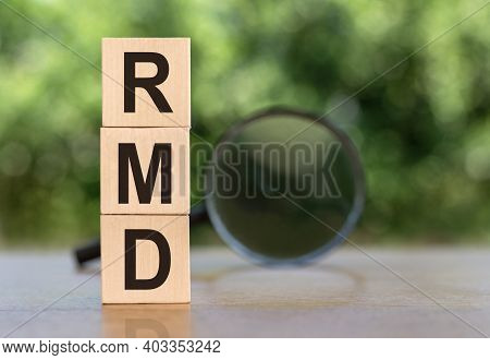 Rmd Word On Wooden Blocks On Table With Magnifier On Green Background.
