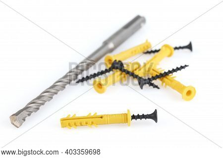 Drill, Dowels And Screws Isolated On White Background. Yellow Plastic Dowel - Fasteners And Concrete