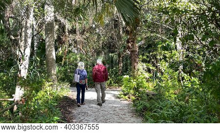 A Senior Couple Walking Along A Tropical Rock Pathway At Mckee Botanical Gardens In Vero Beach, Flor