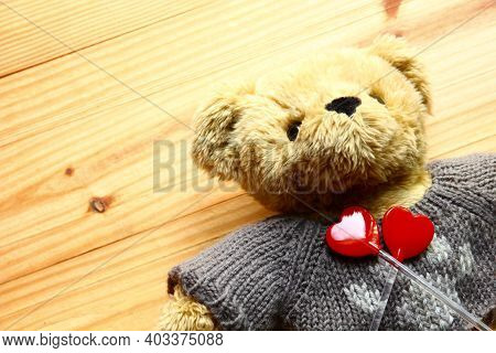 Brown Bear Toy Laying On Wood Background With Two Red Hearts, Valentine Concept