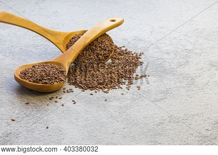 Flax Seeds In A Wooden Spoon On A Concrete Background, A Dietary Product That Reduces Cholesterol, A