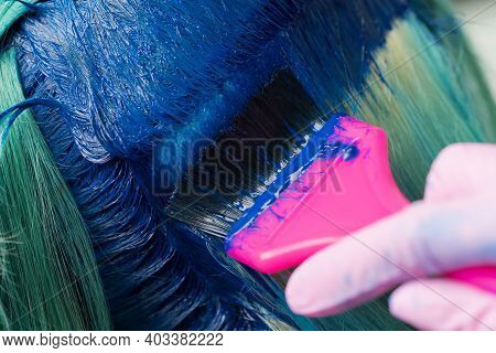 Close-up Of Hair Coloring At Beauty Salon. Hairdresser Using Pink Brush While Applying Blue Paint To