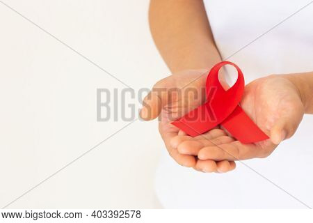 Hands Holding Red Ribbon On White Background Copy Space, Symbol For The Solidarity Of People Living 