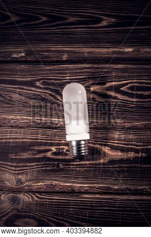White Frosted Flash Pilot Lamp On A Wooden Background. Studio Photo In Hard Light.