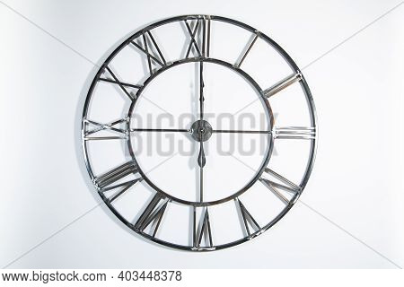 A Metal Openwork Clock With Roman Numerals, Clock Face, Dial On A White Wall, Isolated On A White Ba