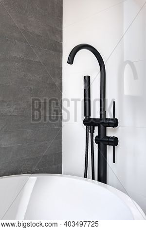 New Black Faucet And Shower Head Against Clean Tiled White And Gray Wall Of Bathroom In Modern Apart