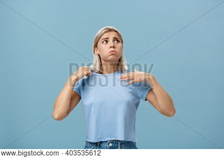 Girl Feeling Discomfort From Heat Standing Over Blue Background In Fug Breathing Out And Frowning Lo