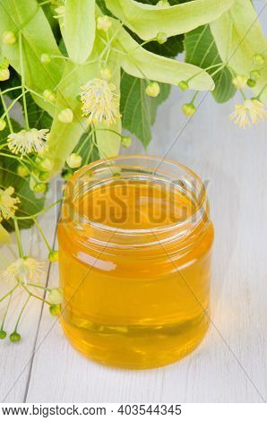 Jar Of Fresh Sweet Linden Honey And Linden Flowers On White Wooden Table