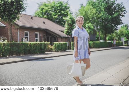 Attractive Blonde In A Short Dress On A Cozy Green Street