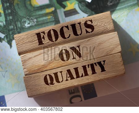 Focus On Quality Words On Wooden Blocks Put On 100 Euro Banknotes. Product Or Service Quality Concep