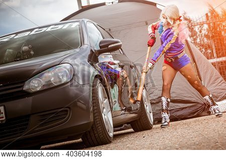 Moscow, Russia - July 06, 2020: Harley Quinn Hits A Parked Black Car With A Baseball Bat. There Is A