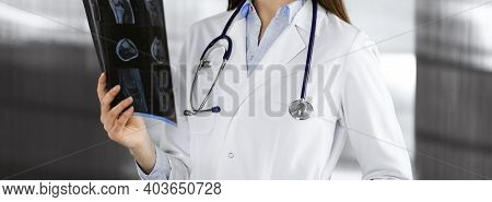 Professional Young Woman Doctor Is Looking At Her Patients Roentgenogram In Clinic. Medicine Concept