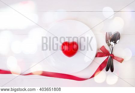 Valentine Day, Heart Shape On Dish And Utensil With Bow For Dinner On Wooden Table, Spoon And Fork W