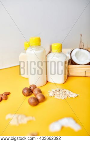 Alternative Types Of Vegan Milks In Bottles On A Yellow Background