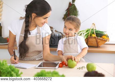 Happy Family In The Kitchen. Mother And Child Daughter Make Menue For Cooking Tasty Breakfest In The