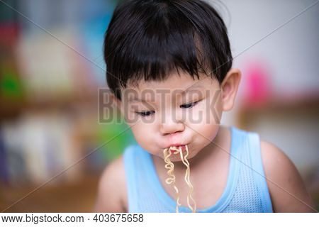 Selective Focus. Child Uses The Mouth To Take The Strands Of Food And Inhale. On A Cloudy Day Childr