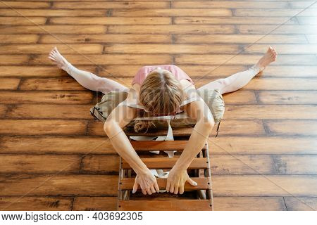 Mature Woman Doing Stretching Exercises On Yoga Backbend Bench In Studio