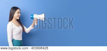 Portrait Of Young Beautiful Smiling Woman Is Using Megaphone To Announce Over Isolated Blue Backgrou