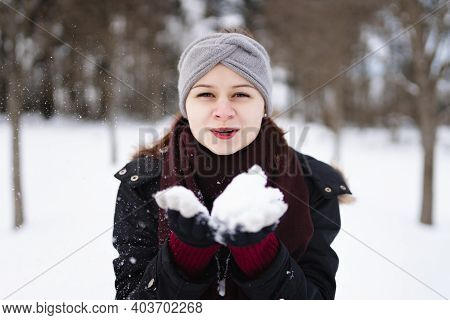 Photo of smiling young girl in winter clothes with snow