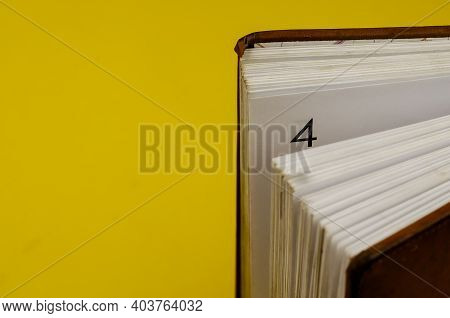 Close-up Of An Old Diary Standing On The Endpaper Against A Yellow Background. Half-opened Diary Wit