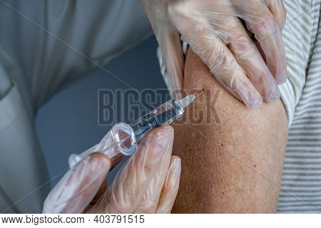 Doctor Giving Injection To Senior Man At Hospital. Nurse Holding Syringe Before Make Covid-19 Or Cor