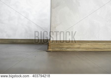 Laminate With Plastic Baseboard With A Wooden Texture. Newly Installed Wooden Laminate Flooring And 