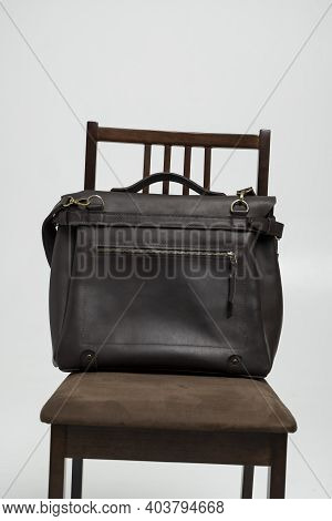 Brown Mens Shoulder Leather Bag For A Documents And Laptop On A Brown Chair With A White Background.