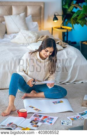 Cute Young Woman Cutting Pistures From Magazines And Making A Wishlist