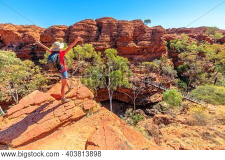 Panoramic View Of Woman At Kings Canyon Rim Walk With Footbridge Over Garden Of Eden, Watarrka Natio