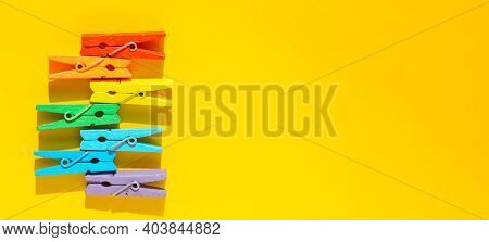 Banner Concept Of Mood-boosting Color, Multi-colored Wooden Multi-colored Clothespins On A Yellow Pa