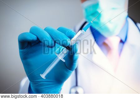 Close Up Hand Of Doctor In Blue Latex Glove And Medical Gauze Mask With Transparent Syringe. Health 