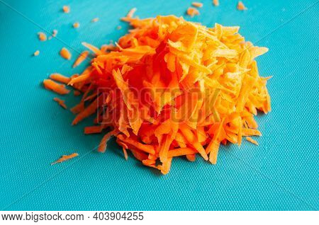 Closeup Fresh Grated Carrot On A Blue Plastic Cutboard