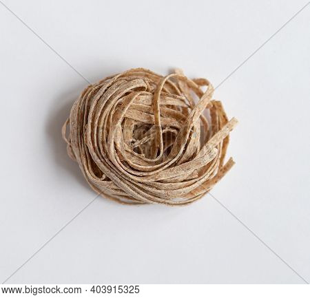 One Portion Raw Whole Grain Brown Pasta On A White Background. Delicate Wholemeal Pasta Made Of Grah