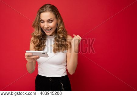Photo Of Happy Smiling Concentrated Beautiful Young Blonde Woman Wearing White T-shirt Isolated On R