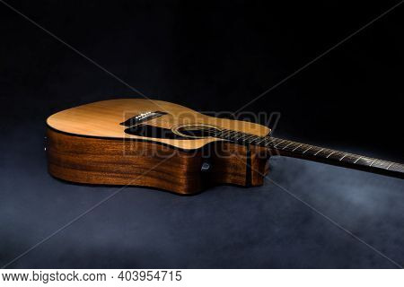 Classical Acoustic Guitar In Yellow With Black Pickguard On Isolated Black Background