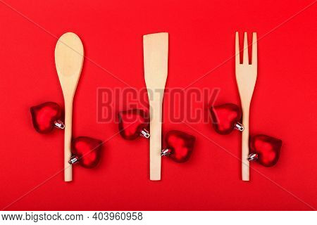 Wooden Kitchen Utensils With Red Hearts On Red Background. Cooking Spoon, Spatula And Fork Like Bran