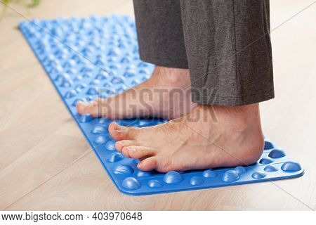 man doing flatfoot correction gymnastic exercise walking on massage mat at home